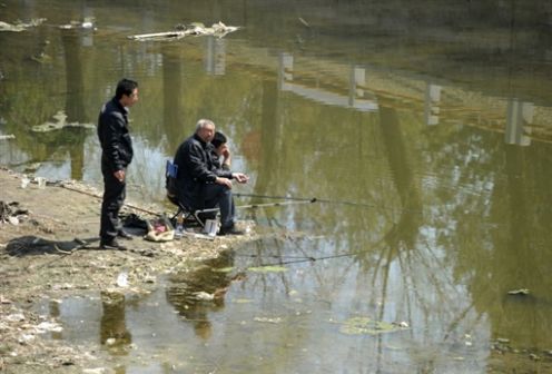 图片： 近年来，中国环境污染问题日渐严重。图为北京的几位市民在已被污染的河上钓鱼。 （法新社资料图片）