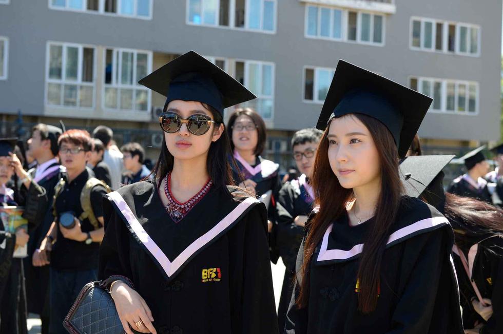 美女学生穿学士服拍毕业照。