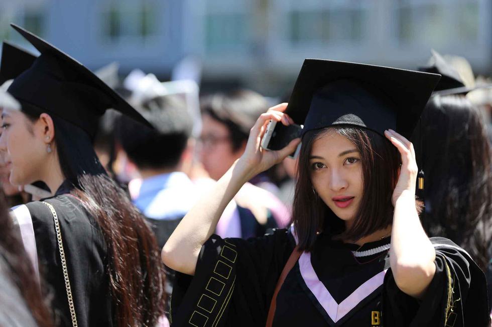 美女学生穿学士服拍毕业照。