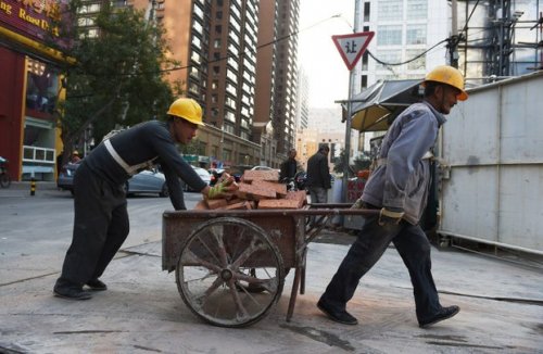 报道，2014年中国劳动年龄人口比上年减少371万人。图为在北京一建筑工地搬运材料的工人。（法新社资料图片）