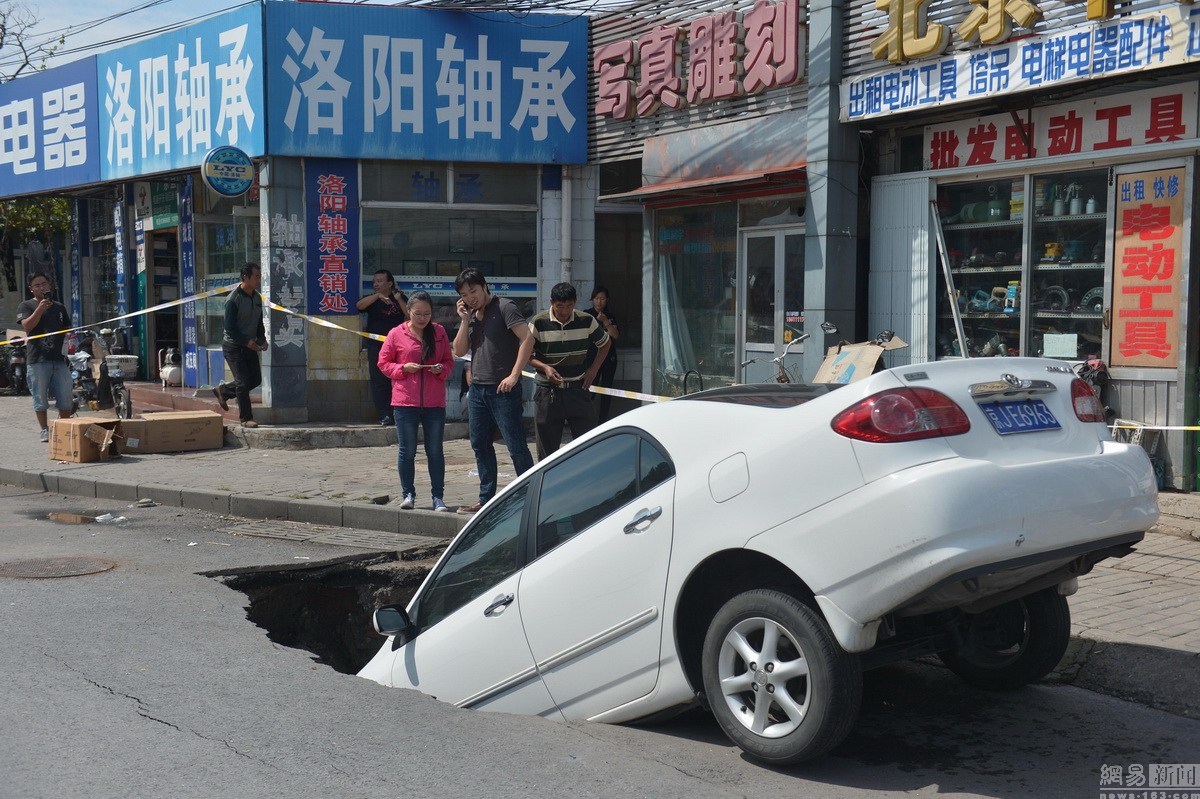 图为北京路面塌陷，一轿车掉入坑中。