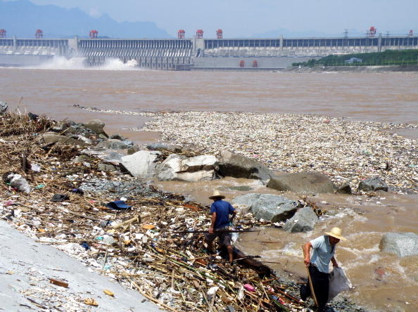 最近，习近平在重庆与11省负责人召开座谈会，习近平在会上说，今后对长江“不搞大开发”。分析认为，习讲话或释放追责三峡工程的信号。图为长江三峡大坝附近两名工人清理沿岸垃圾。(STR/AFP/Getty Images)