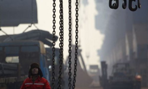 2012年2月20日河北省唐山曹妃甸港的一名码头工人等待把钢筋装上货轮。（网络资料图片）