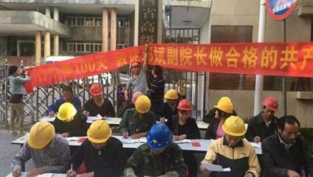 5月23日，20多名头戴安全帽的工人，围坐在江西省高级法院门口抄写党章，背后还拉着一张条幅。（网络图片）