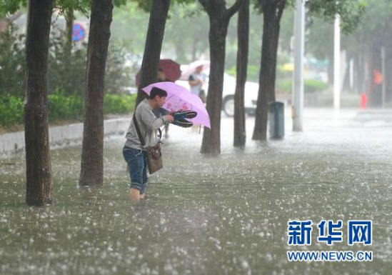 7月20日，一位石家庄市民在槐安路一处积水路段脱鞋涉水出行。新华社记者朱旭东摄