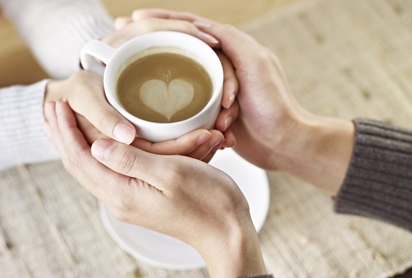 hands of young lovers holding a cup of coffee.