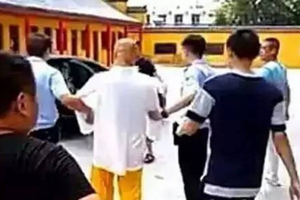 张立伟（穿白衣者）16年前因杀人而被通缉，而后藏身寺庙16年。日前因申请护照，指纹暴露身份而被捕。（网络截图）